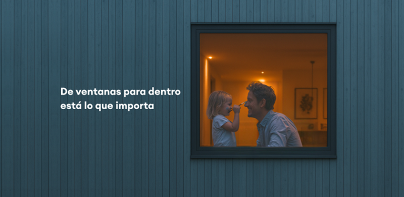 Se ve a través de una ventana a un padre junto a su hija en el interior de la vivienda