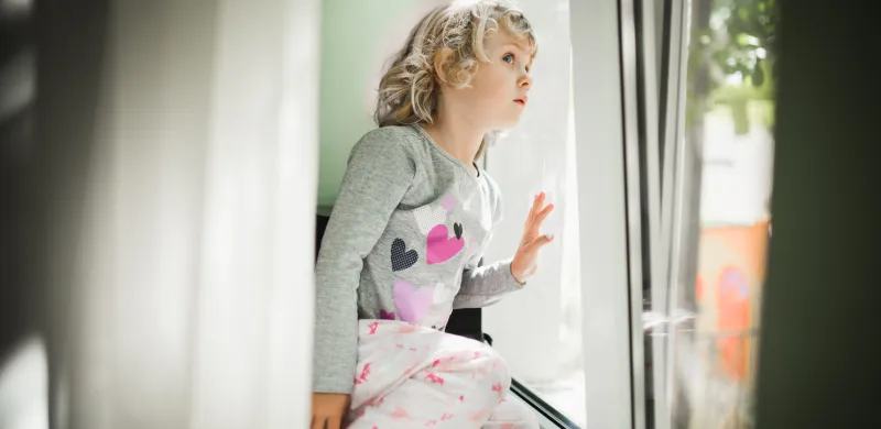Niña mirando al exterior a través de una ventana de PVC con aislamiento acústico