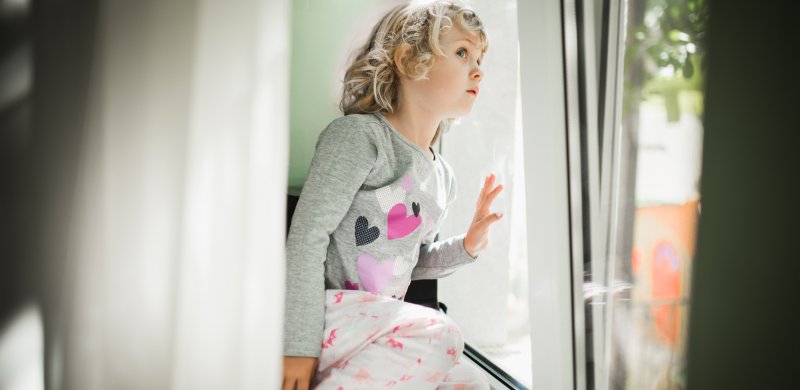 Niña mirando al exterior a través de una ventana de PVC con aislamiento acústico